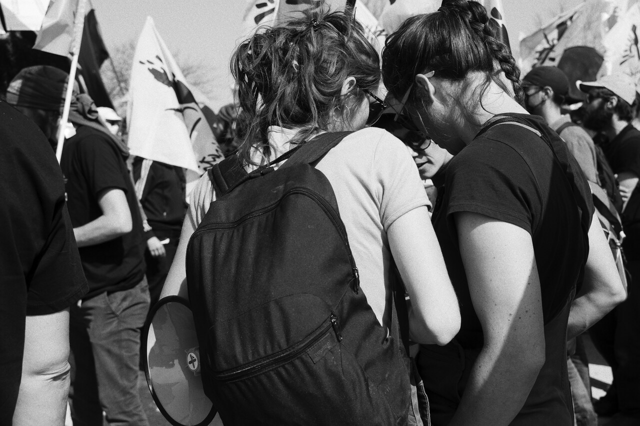 LE BRIEF AVANT L'ACTION <br>La marche s'ébranle et chacun.e a reçu les instructions nécessaires pour conduire les groupes en différents points stratégiques du parcours et de la marche qui doit se déployer sur la route et dans les champs, le long de la zone interdite où sont postés les escadrons de la gendarmerie mobile. Déjà l'hélicoptère a repris son ballet aérien.<br>